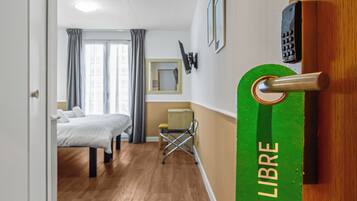 Una habitación de hotel con cama, una silla, un escritorio y un minibar.