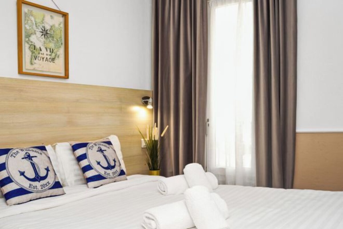 A hotel room with a wooden headboard, a framed map on the wall, and a bed with rolled white towels.
