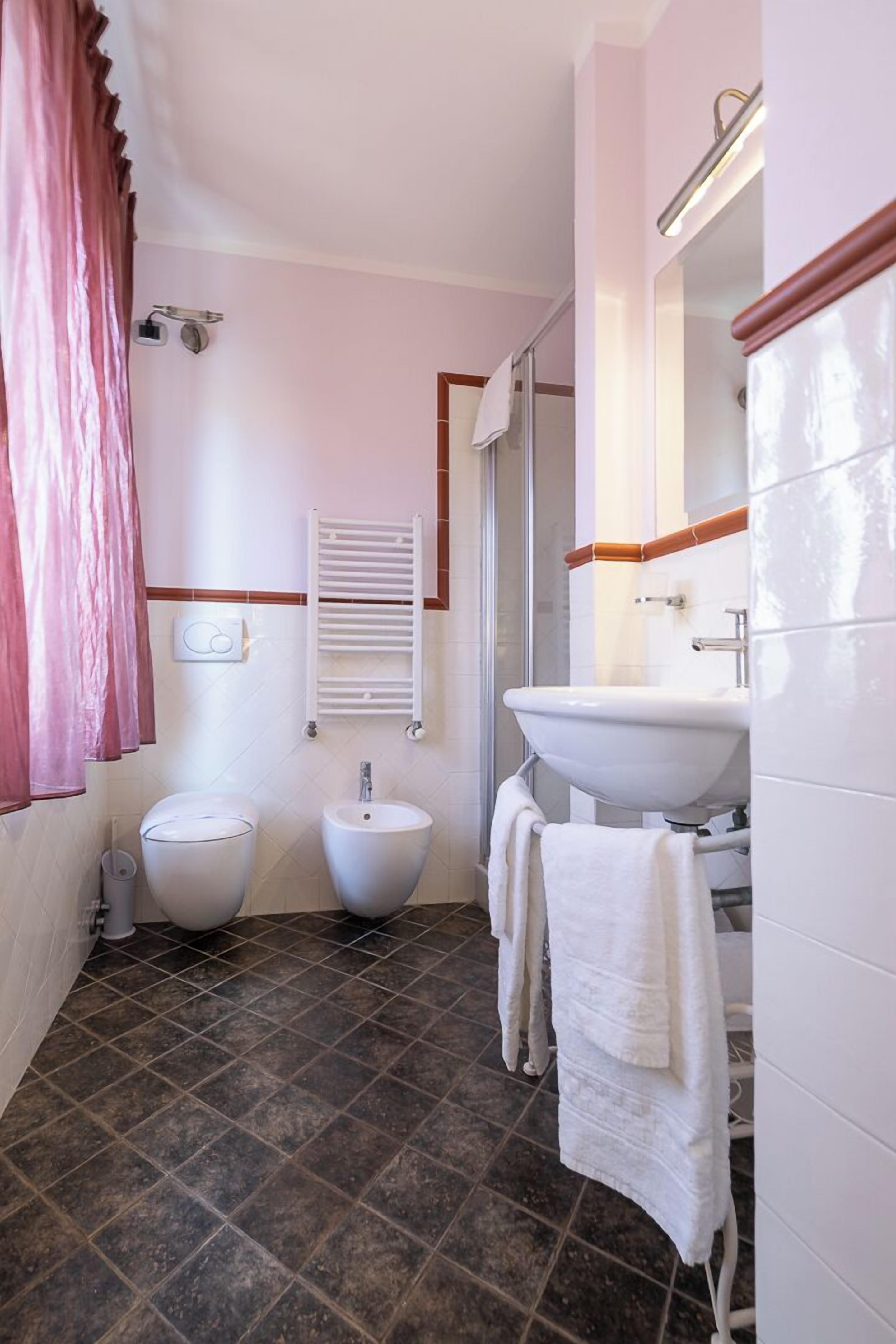 Une salle de bain comprenant des toilettes, un bidet, un lavabo et un porte-serviettes.