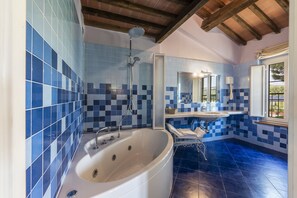 Bathroom features a bathtub, blue and white tile walls, and a wooden ceiling with exposed beams.