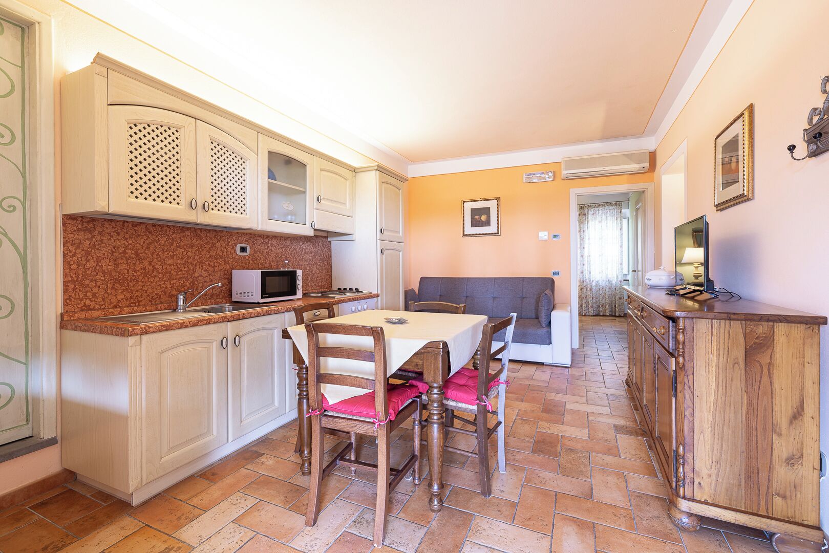 A compact kitchen with a dining table and chairs, a microwave, and a sink.