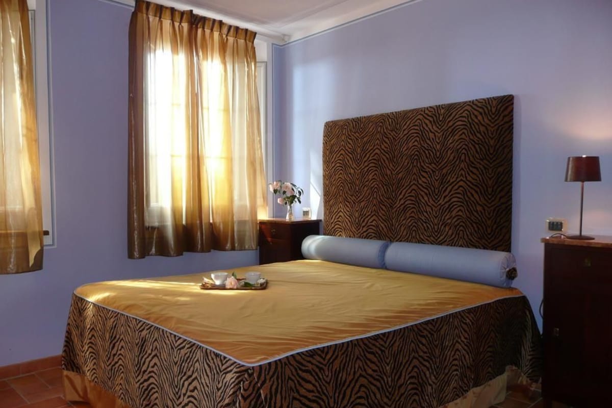 Une chambre avec un lit, des rideaux, une table de chevet et une lampe.
