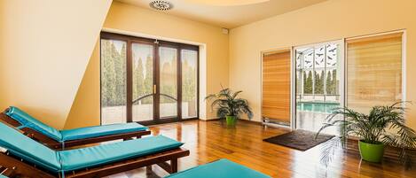 Una habitación con pisos de madera, un ventanal con persianas y una lámpara en el techo.