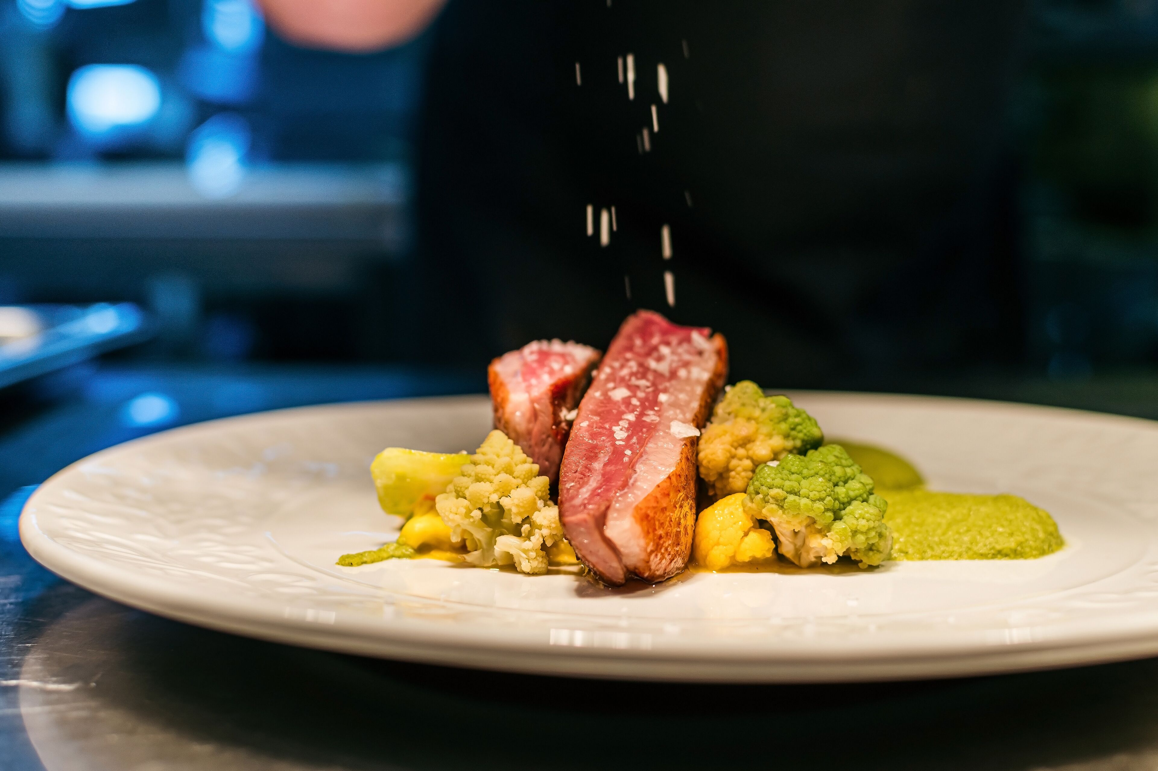 A plate of food with a piece of meat, mashed potatoes, and green sauce.