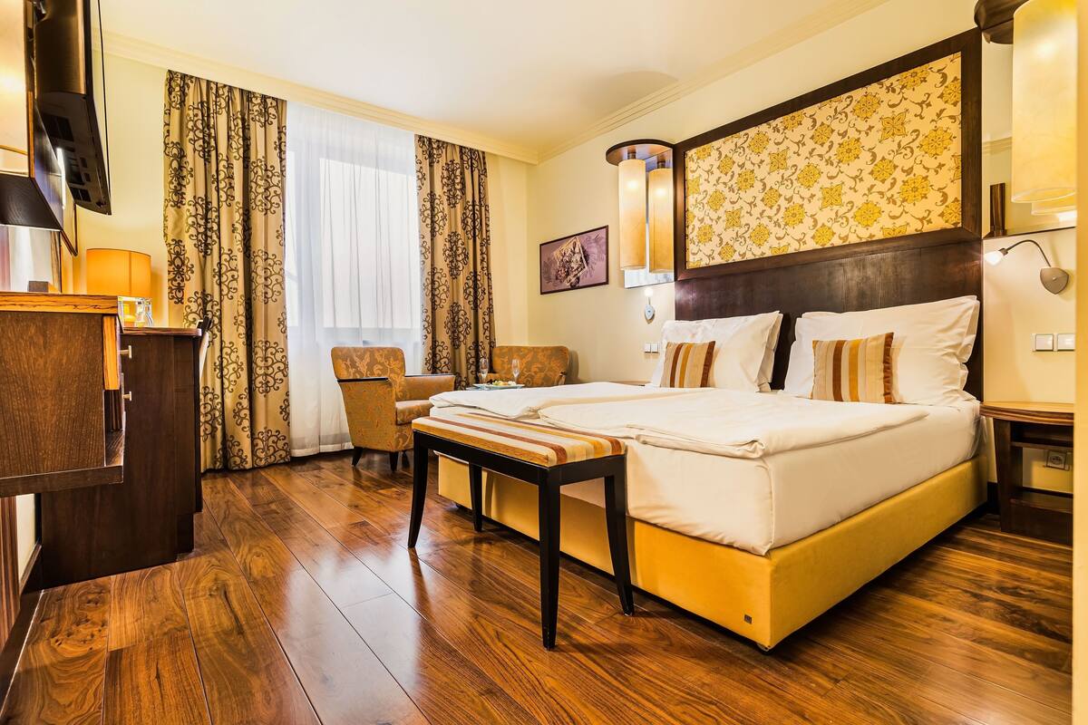 A hotel room with a large bed, a desk, a chair, and a TV.