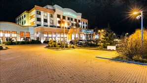 A hotel with a modern design, featuring a prominent sign, a paved entrance, and a well-lit outdoor area.