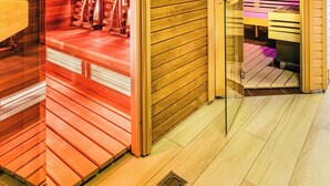 A sauna room with wooden walls and a glass door, a bench, and a bench with a towel.