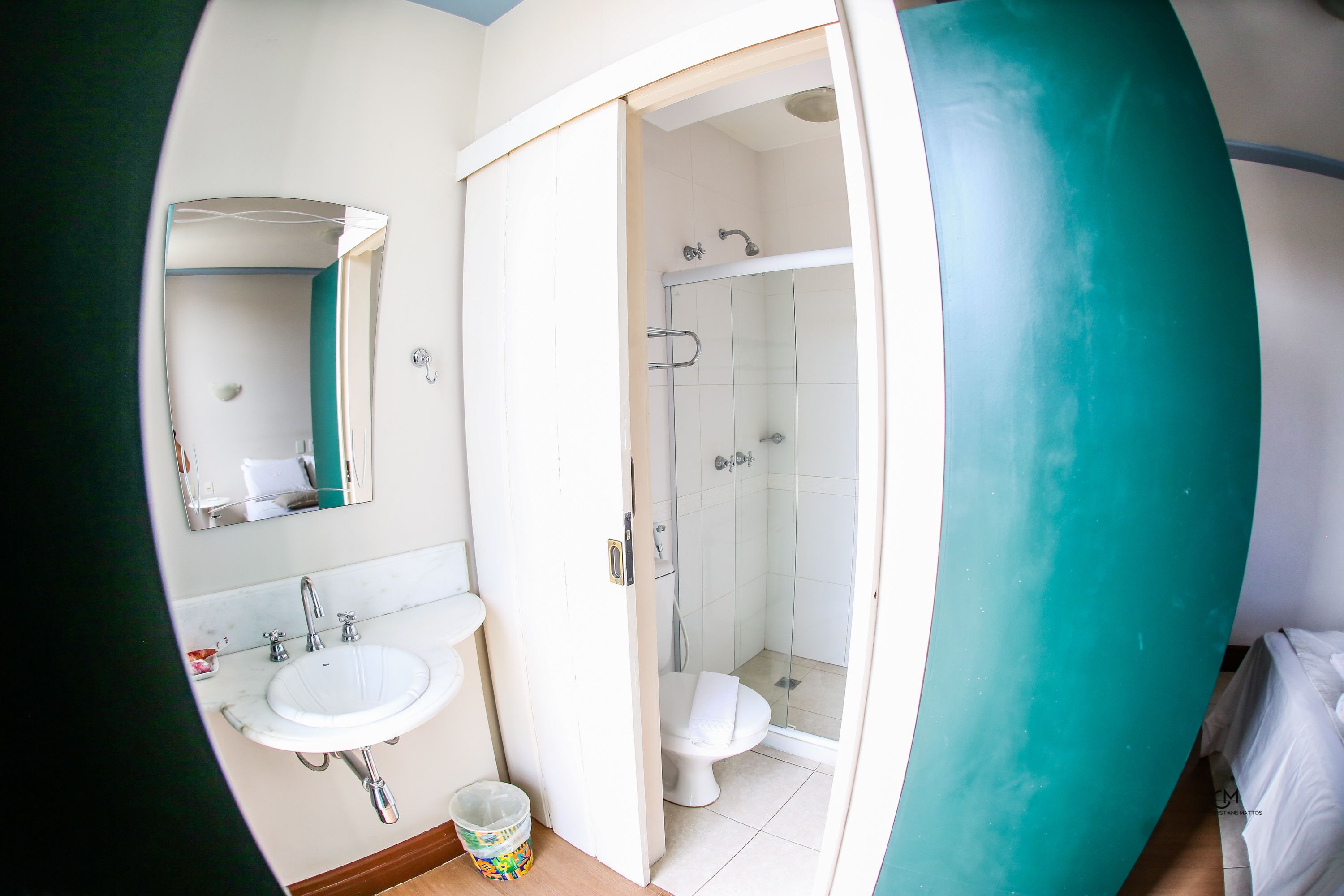 A bathroom with a sink, mirror, toilet, and shower.
