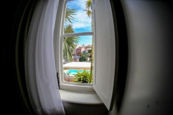 Una ventana con vista a una piscina y palmeras.