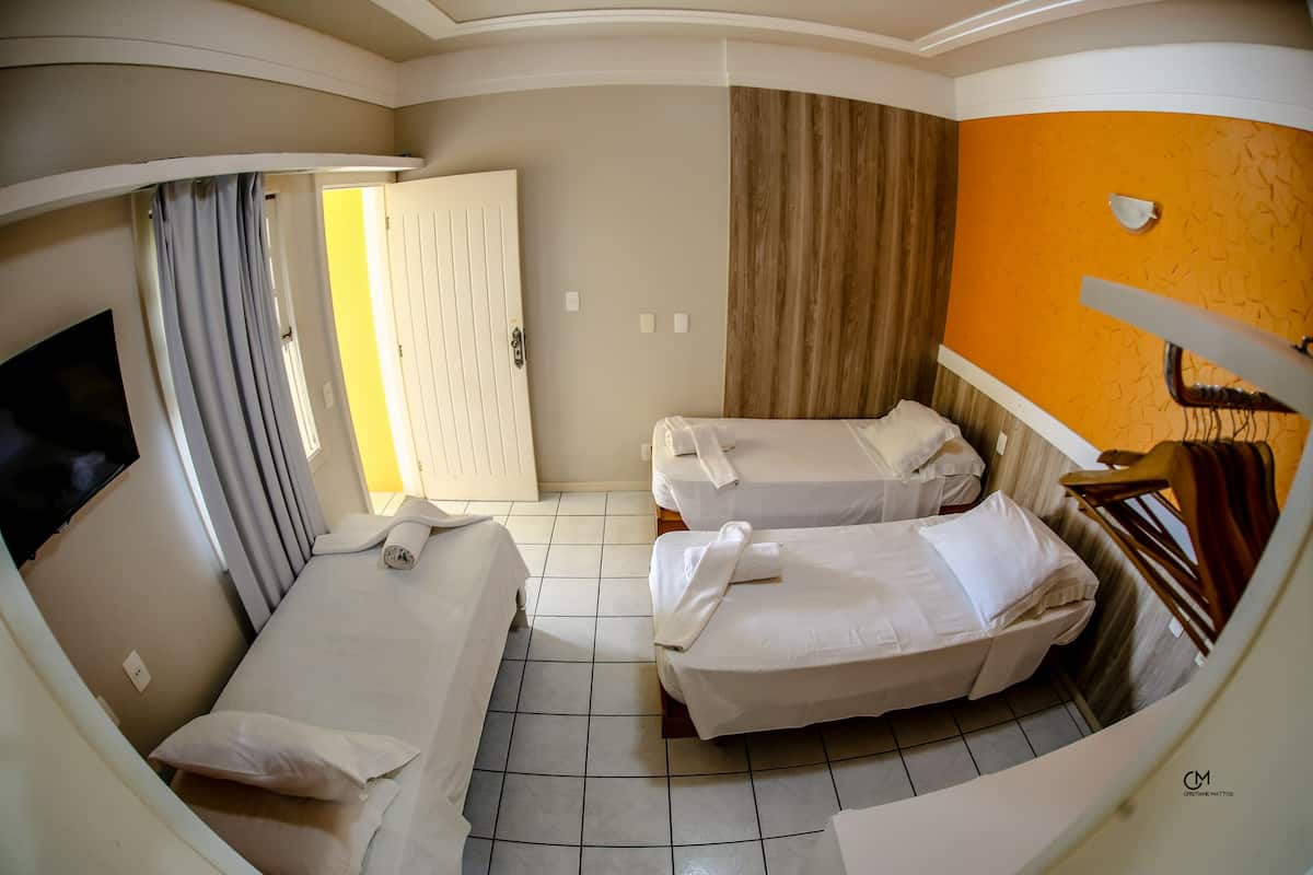 Una habitación con dos camas individuales, televisión, armario y puerta al baño.