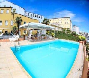 Una piscina al aire libre, sombrillas, sillones reclinables de piscina