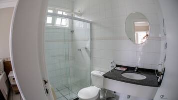 Ein Badezimmer mit einer in Glas eingefassten Dusche, einer weißen Toilette und einem Waschbecken mit Granitplatte.