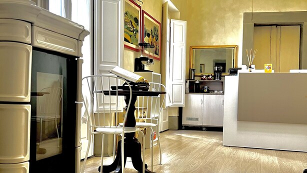 A modern kitchen with white cabinetry, a dining area with a white chair, and a hanging yellow light fixture. - B & Beatrice (Florence)
