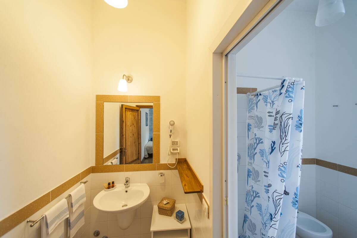 Un bagno con lavandino, specchio, porta asciugamani e tenda doccia.