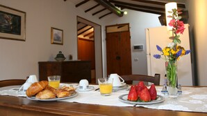 A breakfast table with croissants, strawberries, orange juice, and a vase of flowers. - La Coperta Ricamata (Siena)