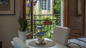 A balcony with a table, chairs, a potted plant, a hanging planter with flowers, and a decorative lantern. - La Coperta Ricamata (Siena)
