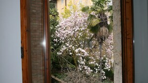 A window with a view of a building and flowering trees. - La Coperta Ricamata (Siena)