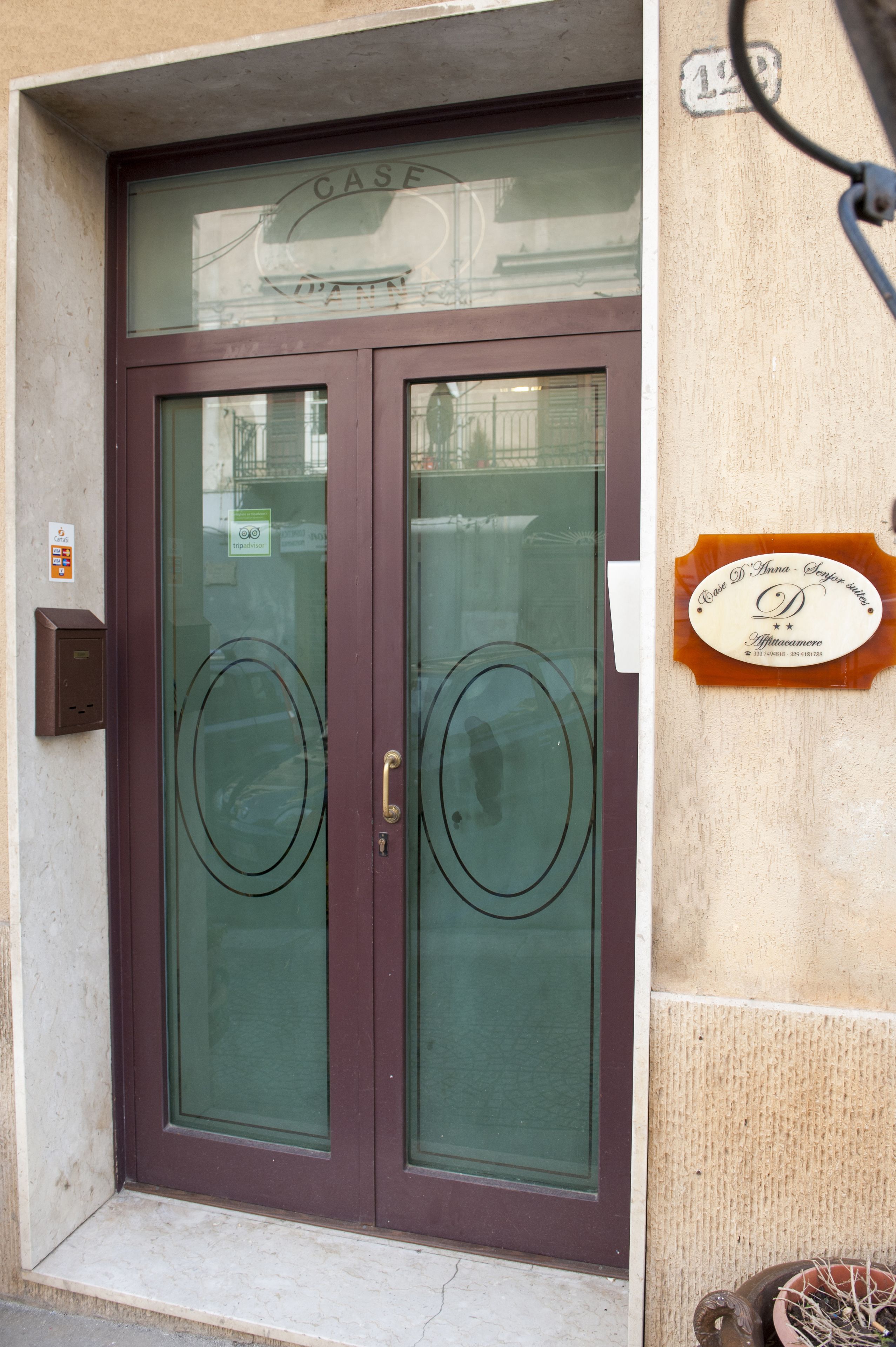 A double door with frosted glass panels, a plaque on the wall, and a mailbox.