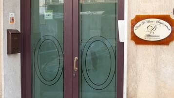 A double door with frosted glass panels, a plaque on the wall, and a mailbox.