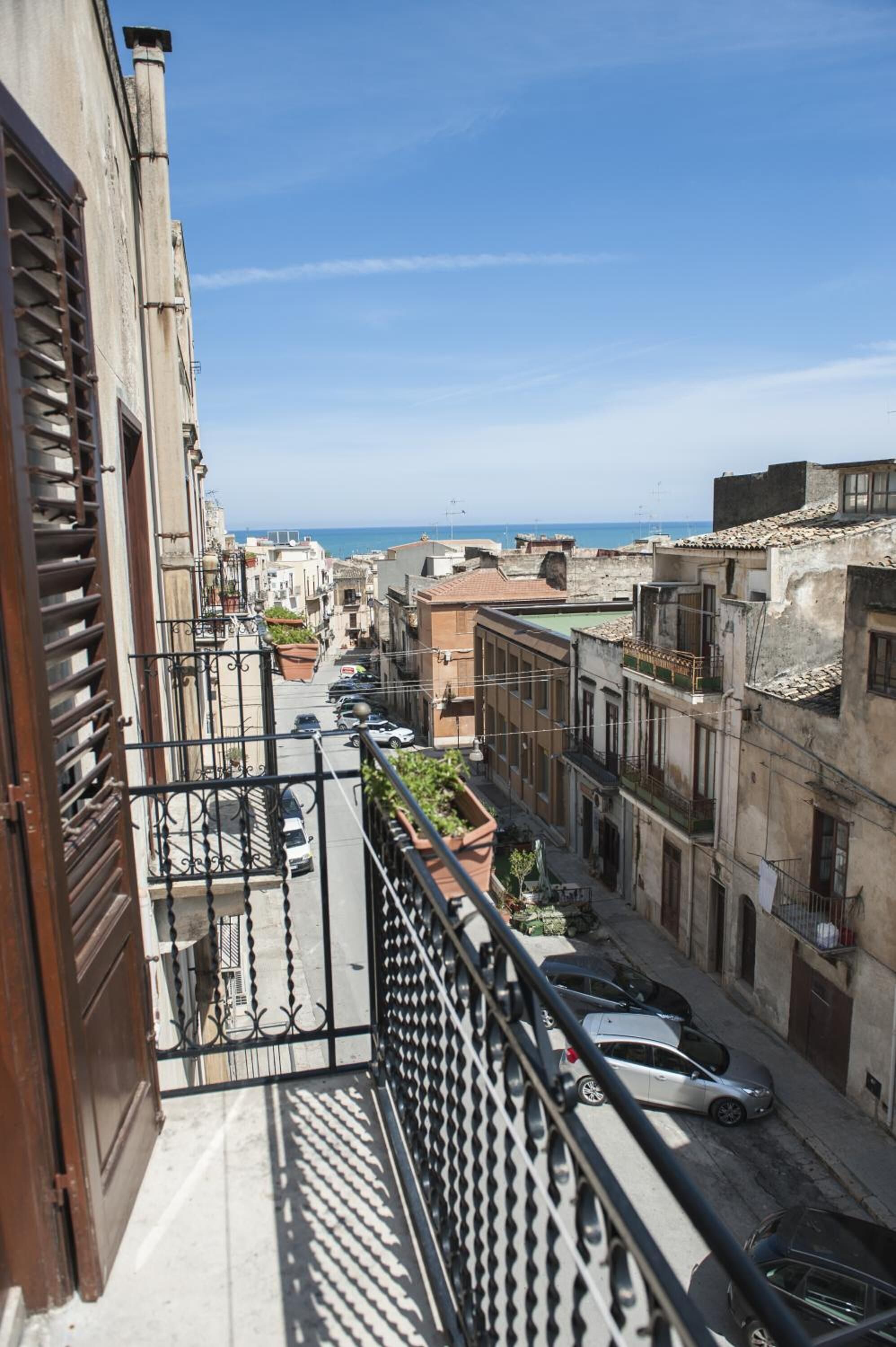 Una stretta via fiancheggiata da edifici, cielo sereno e vista sul mare in lontananza.
