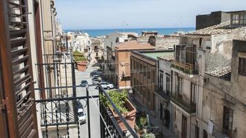 Una stretta via fiancheggiata da edifici, cielo sereno e vista sul mare in lontananza.