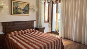 Un dormitorio con una cama grande, una araña de techo, un cuadro y vistas al exterior.