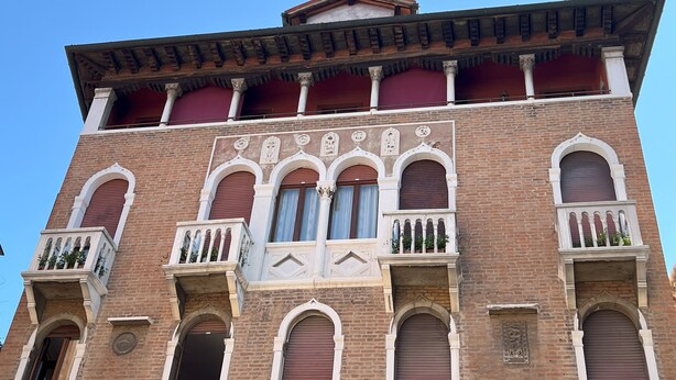 Un edificio histórico con varios balcones, ventanas arqueadas y detalles decorativos de ladrillo.