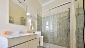 Une salle de bain moderne avec une douche à parois de verre, un grand miroir et un meuble-lavabo blanc.