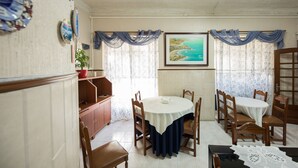 Un coin repas avec une table ronde, des chaises en bois, une plante en pot et un tableau accroché au mur.