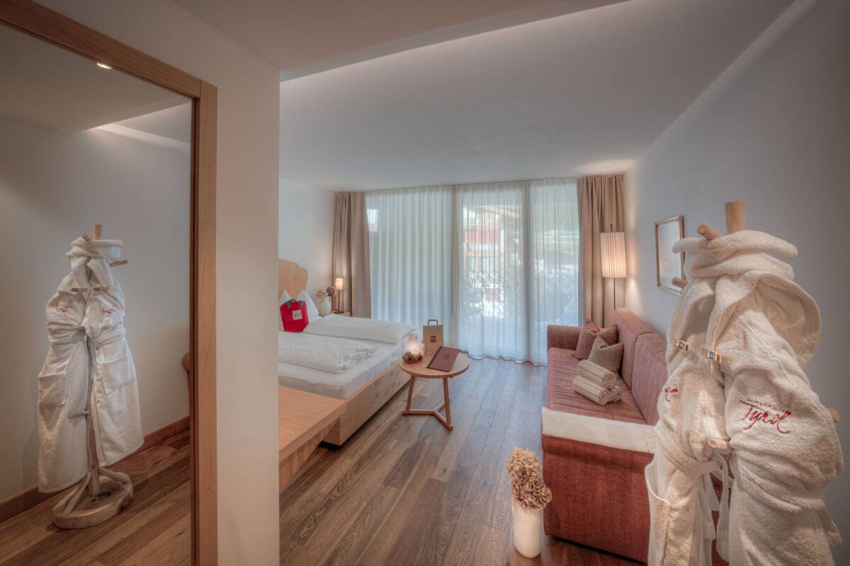 Een hotelkamer met een bed, een bank, een kleintje tafeltje en een spiegel.