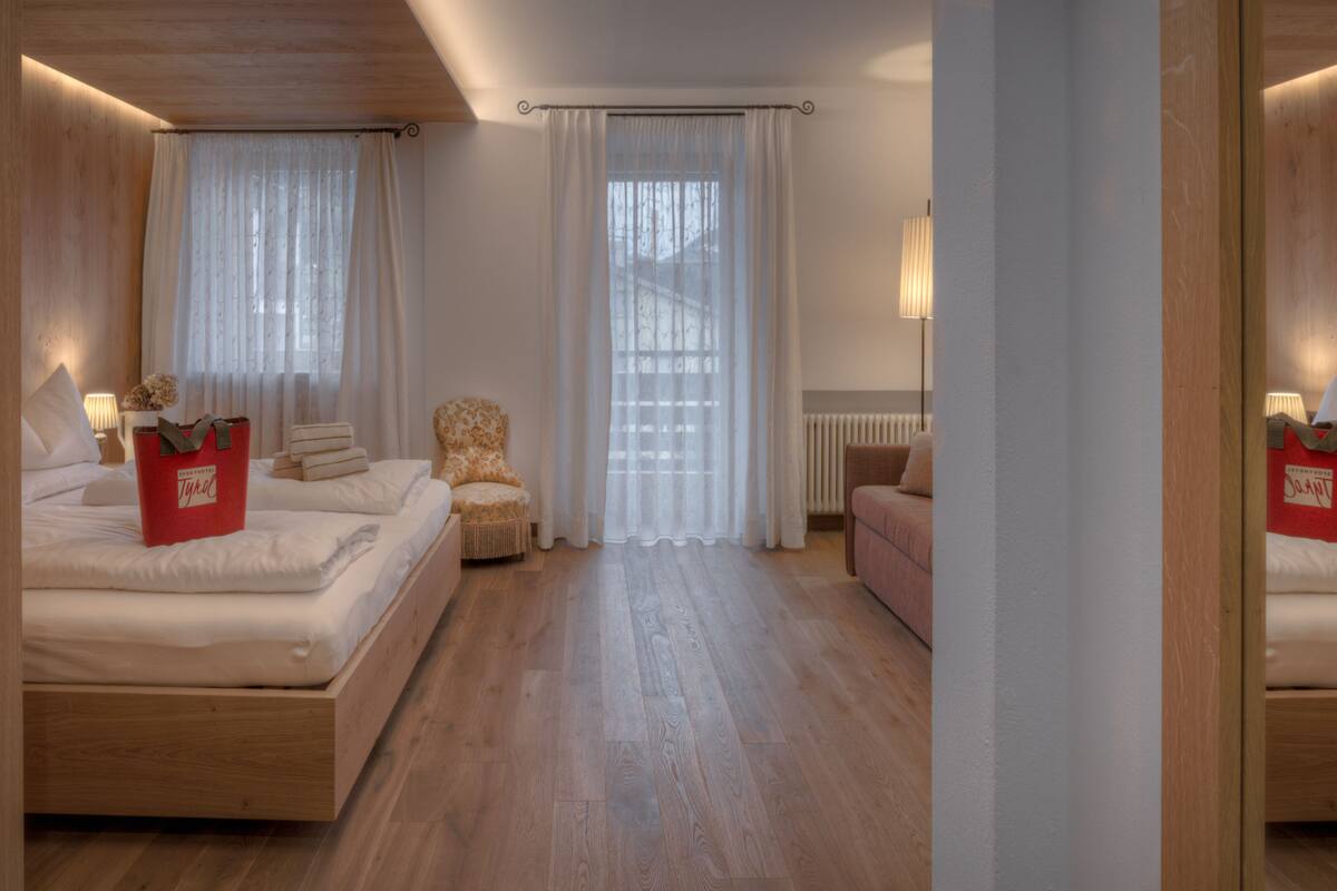 Een hotelkamer met twee bedden, een stoel, een bank en een spiegel.