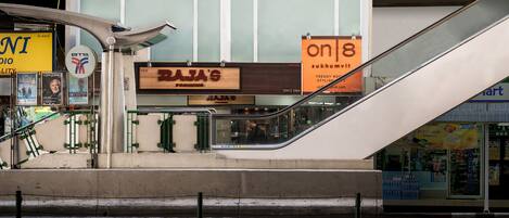An escalator leading to a building with a sign for 'Raj's' and 'on8' on the side.