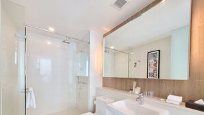 Un baño moderno con cabina de ducha de vidrio, un lavabo blanco y un inodoro.