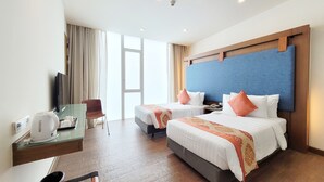 Habitación de hotel con dos camas, un escritorio con cafetera, una silla y un televisor.
