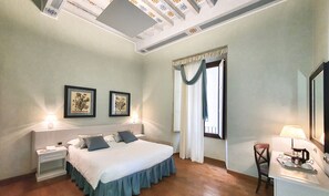 A hotel room with a bed, bedside tables, a desk with a lamp, a chair, and a window with curtains. - La Signoria di Firenze (Florence)