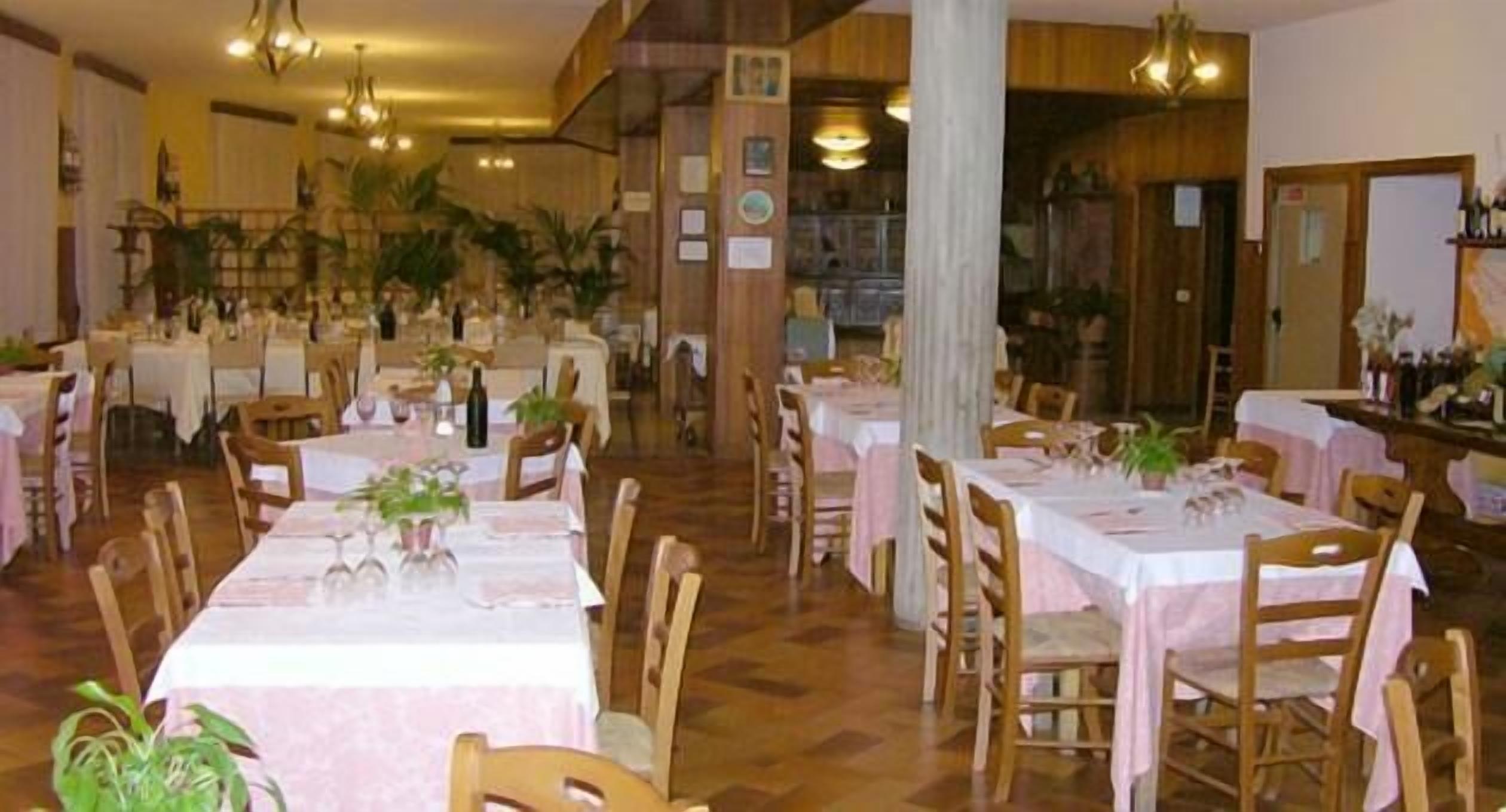 Un restaurant avec plusieurs tables, des chaises en bois et des plantes en pot.