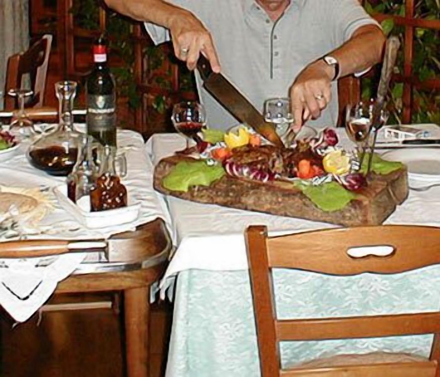 Una mesa de comedor con un pastel grande y decorado, copas de vino y una botella de vino.