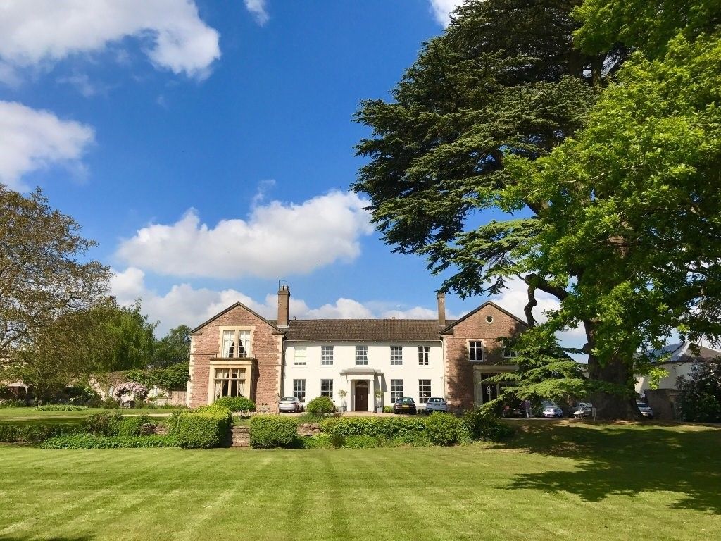 A large, two-story brick building with a symmetrical facade, a central entrance, and a well-maintained lawn in front.