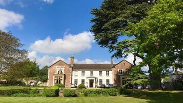 A large, two-story brick building with a symmetrical facade, a central entrance, and a well-maintained lawn in front.