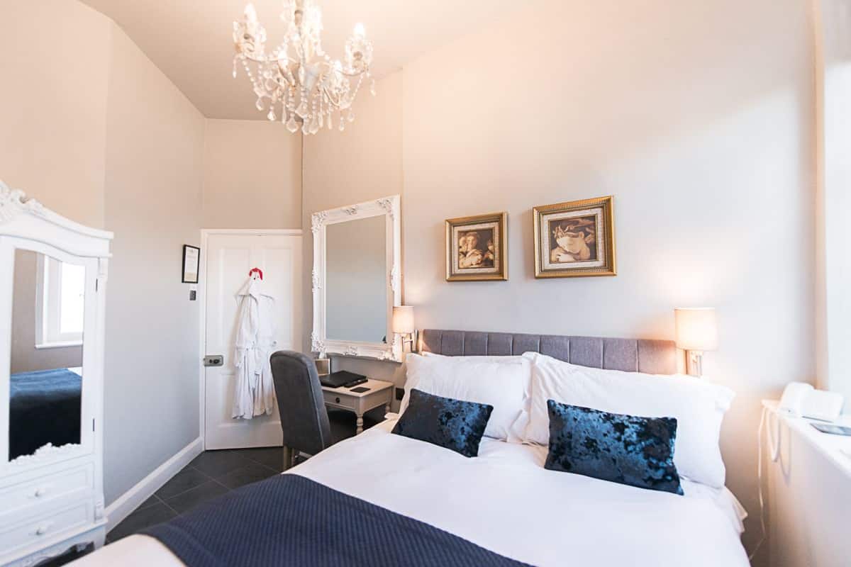 Une chambre d’hôtel avec un grand lit, un bureau, une chaise, un peignoir et un miroir.
