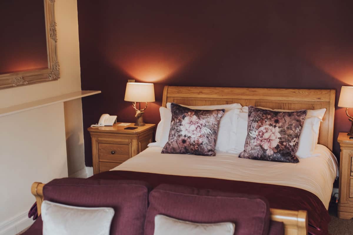 Une chambre d’hôtel avec un grand lit, deux tables de chevet, une petite table et un coin salon comprenant un canapé et des fauteuils.