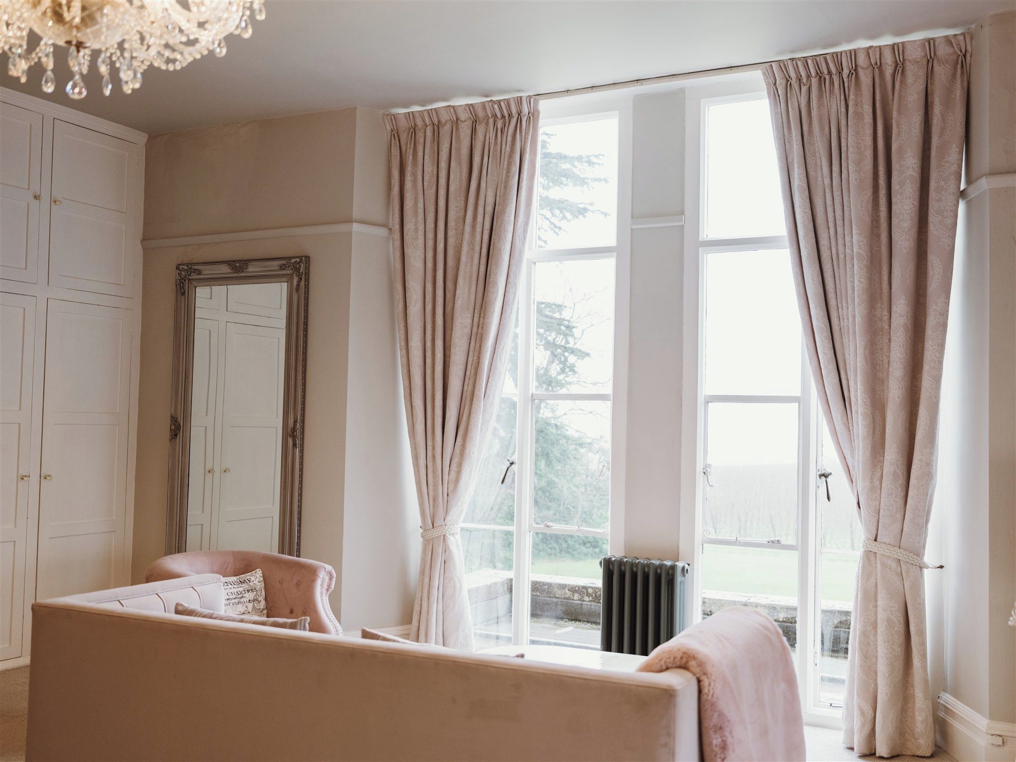 A room with a large window, a radiator, a bed, and a wardrobe.