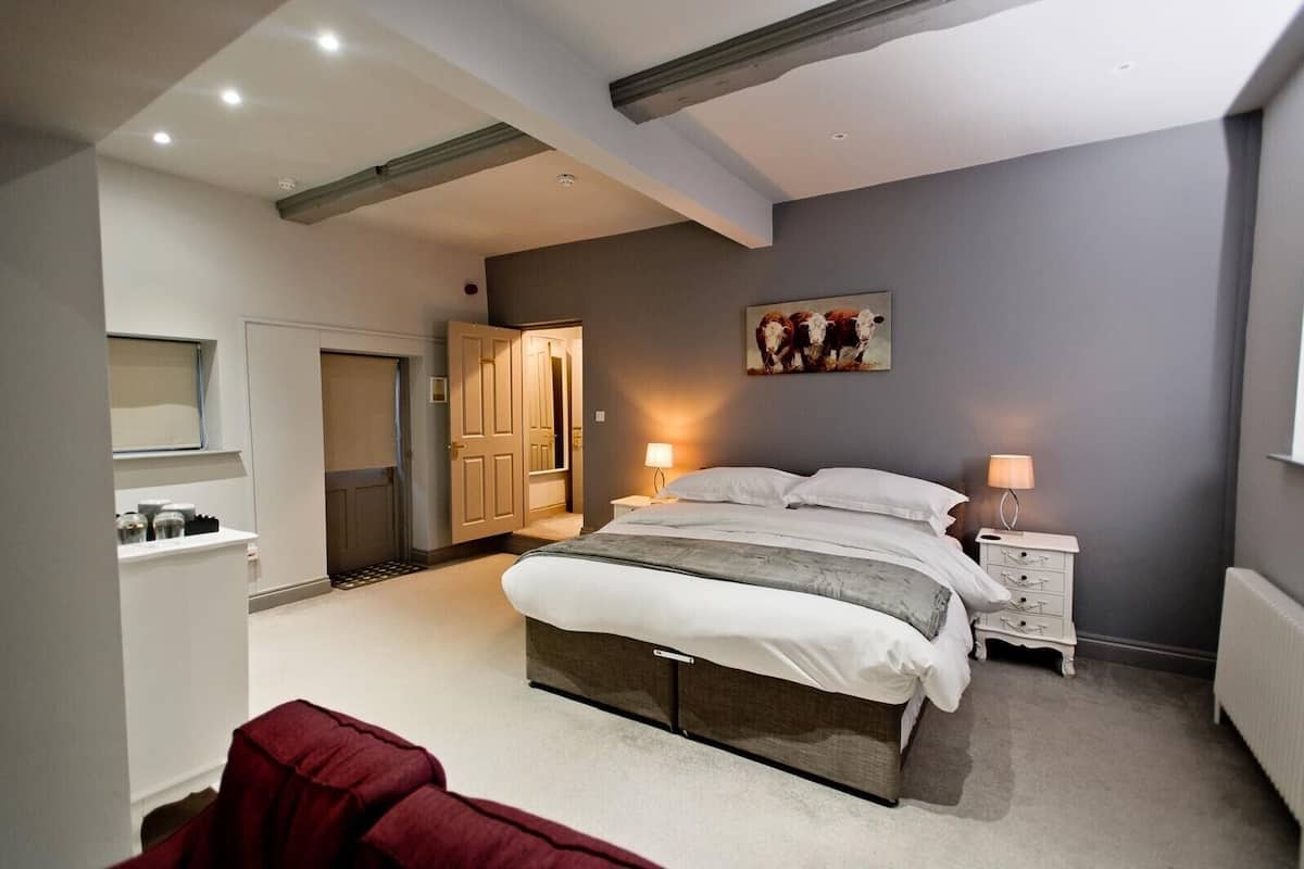 Une chambre à coucher avec un grand lit, des tables de chevet avec des lampes, une armoire et un tableau au mur.