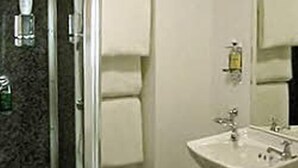 Un baño con cabina de ducha de vidrio, un lavamanos con espejo y un perchero para toallas.
