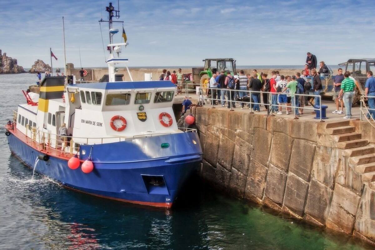 A boat docked at a pier with a crowd of people on the pier.