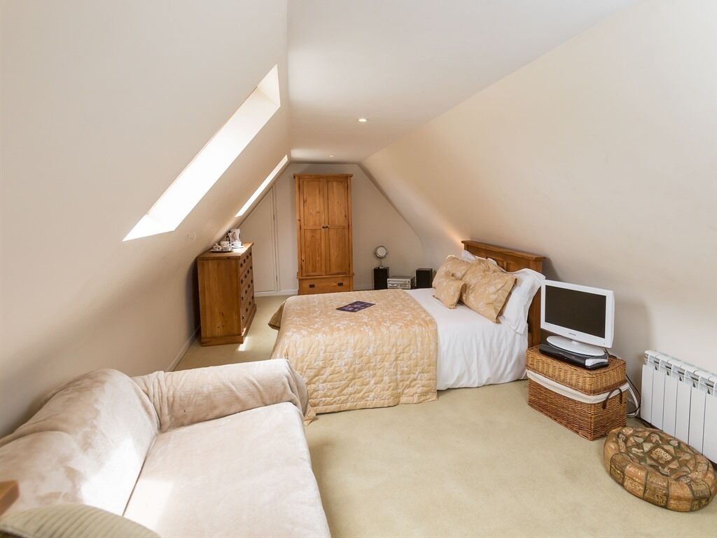 Ein Schlafzimmer mit Bett, Fernseher, Schminktisch und Fenster.