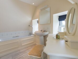Un baño con bañera, lavamanos, tocador y un espejo grande.