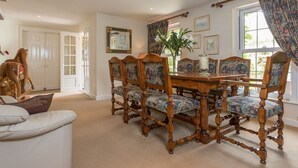 A dining room with a wooden table and chairs, a potted plant, and framed artwork on the walls. - Clos De Vaul Creux (Sark)