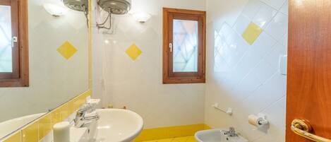 A bathroom with two sinks, a bidet, and a toilet. There are mirrors above the sinks and a window above the bidet.