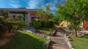 A pathway leading to a building with a tiled roof, surrounded by greenery and a small garden. - Palau Green Village (Palau)